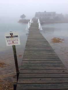 a wooden dock with a no trespassing private bridge sign in the foreground