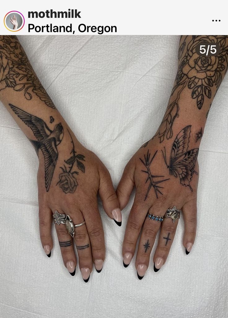 two hands with tattoos and rings on them