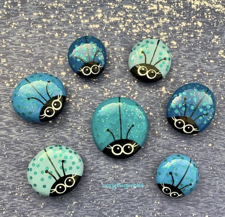 six ladybug buttons sitting on top of a gray surface with gold flecks