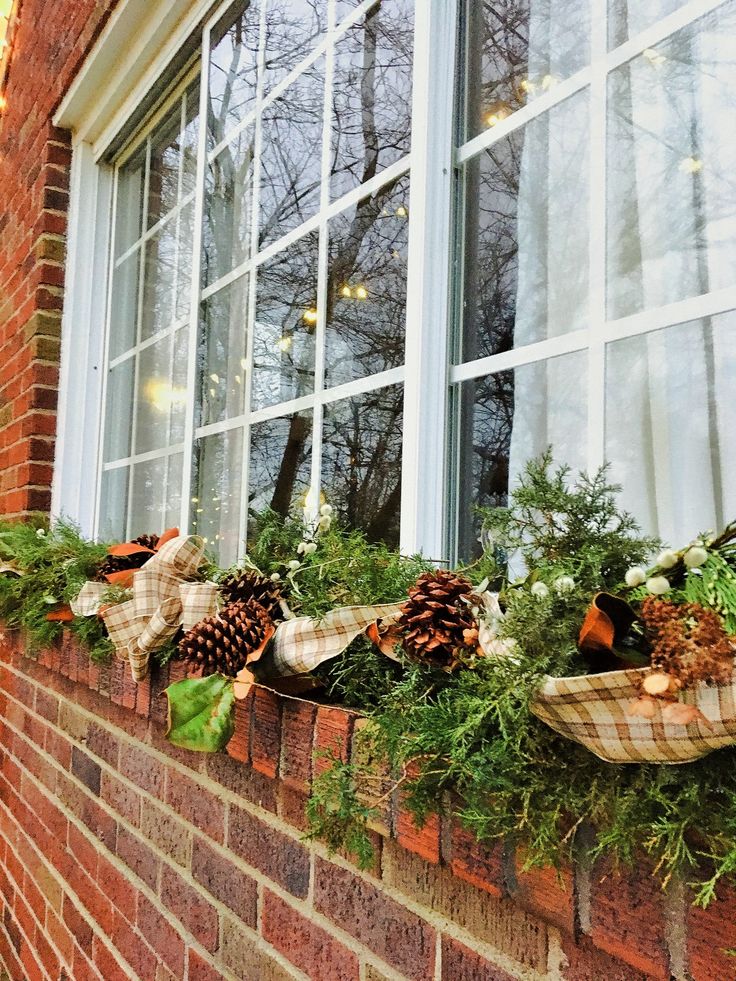 the window sill is decorated with pine cones and greenery