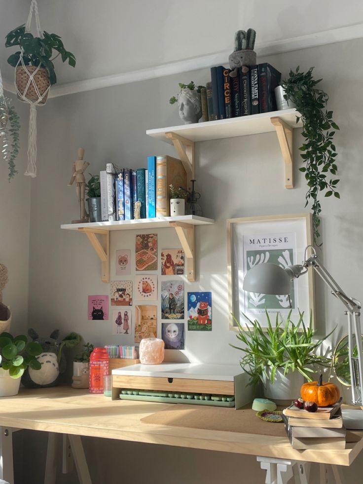 a wooden desk topped with books and plants next to a wall mounted shelf filled with books