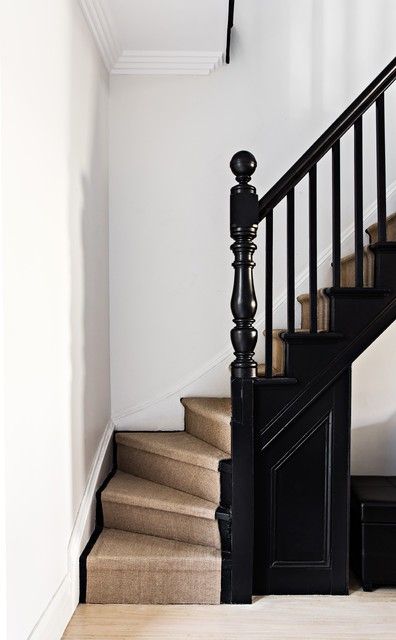 a staircase with black railing and white walls