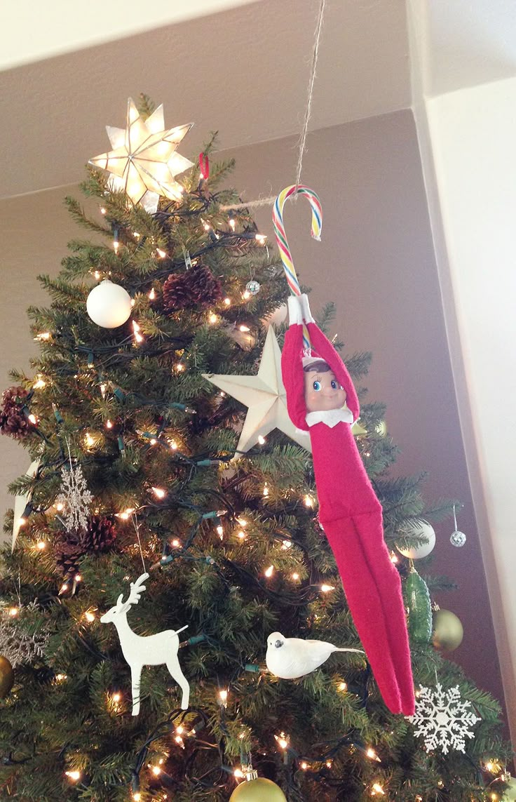 an elf hanging from the top of a christmas tree