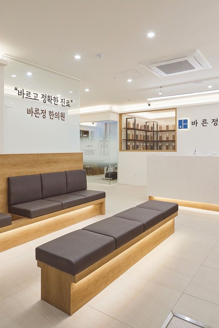 an empty waiting room with benches and signs on the wall behind it in korean language