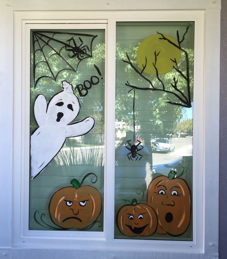 a window decorated to look like halloween with ghost and pumpkins