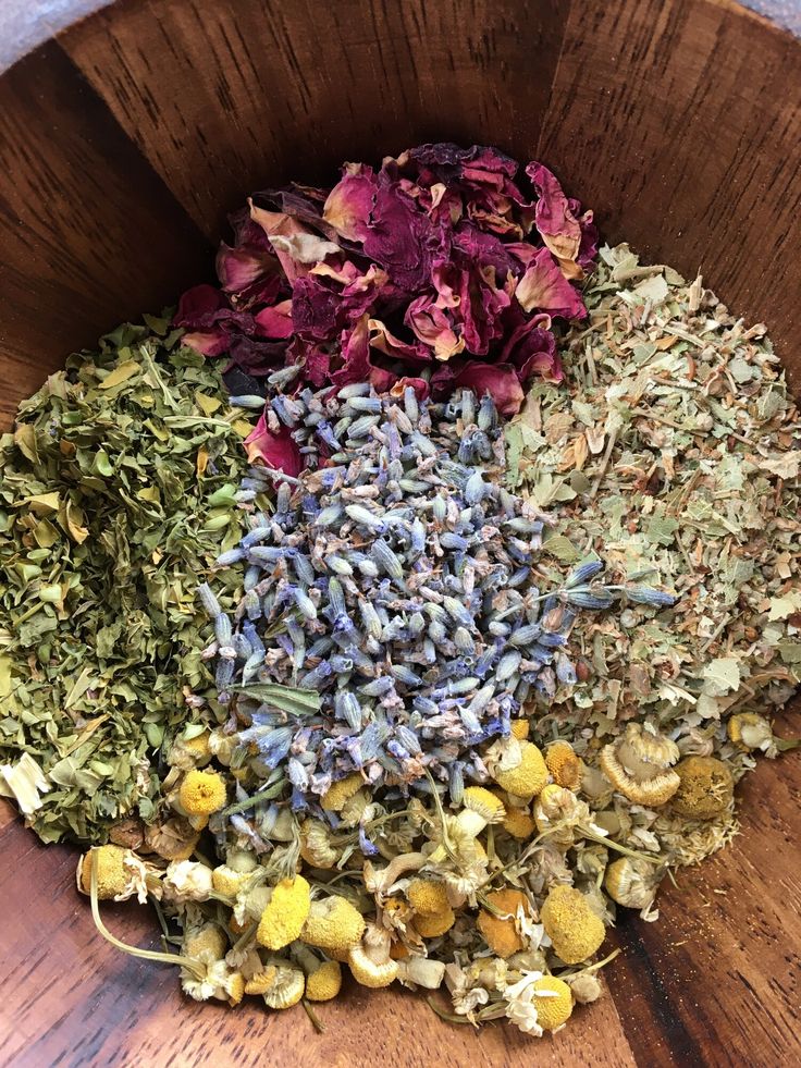 a wooden bowl filled with different types of herbs