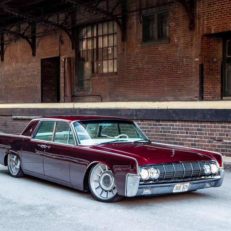 an old car parked in front of a brick building