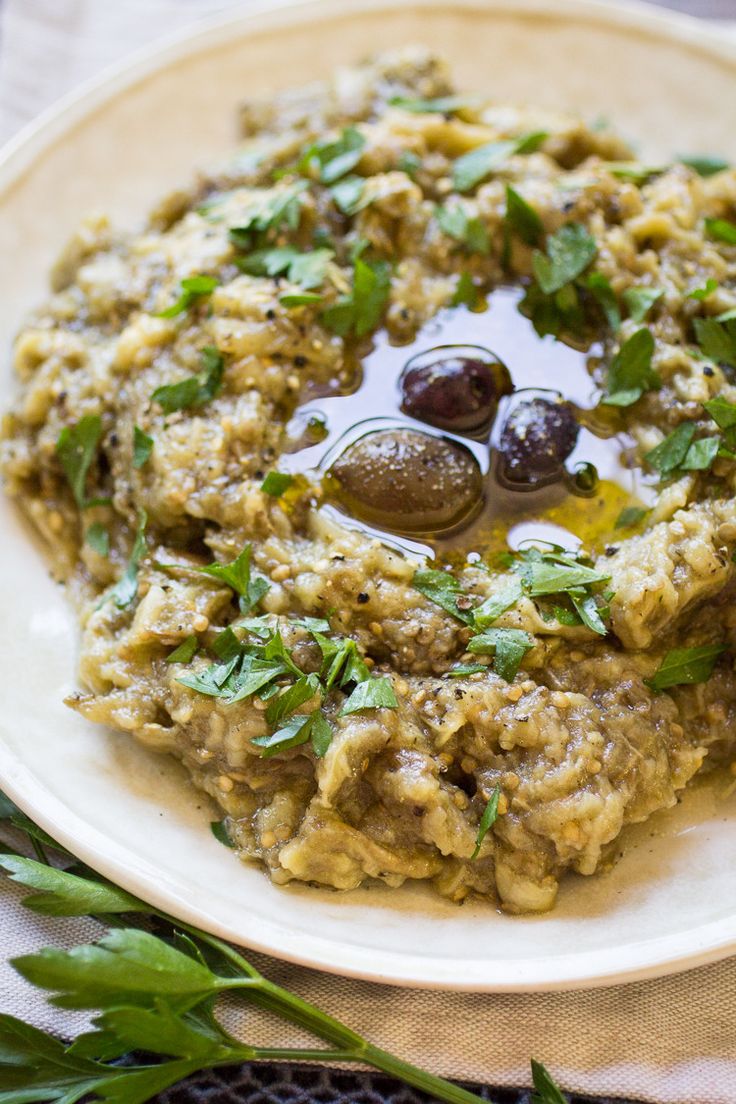 a white plate topped with food covered in olives