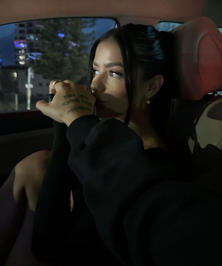 a woman sitting in the back seat of a car with her hand on her chin