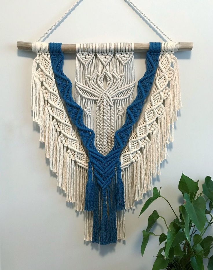 a macrame wall hanging with blue and white tassels on the side