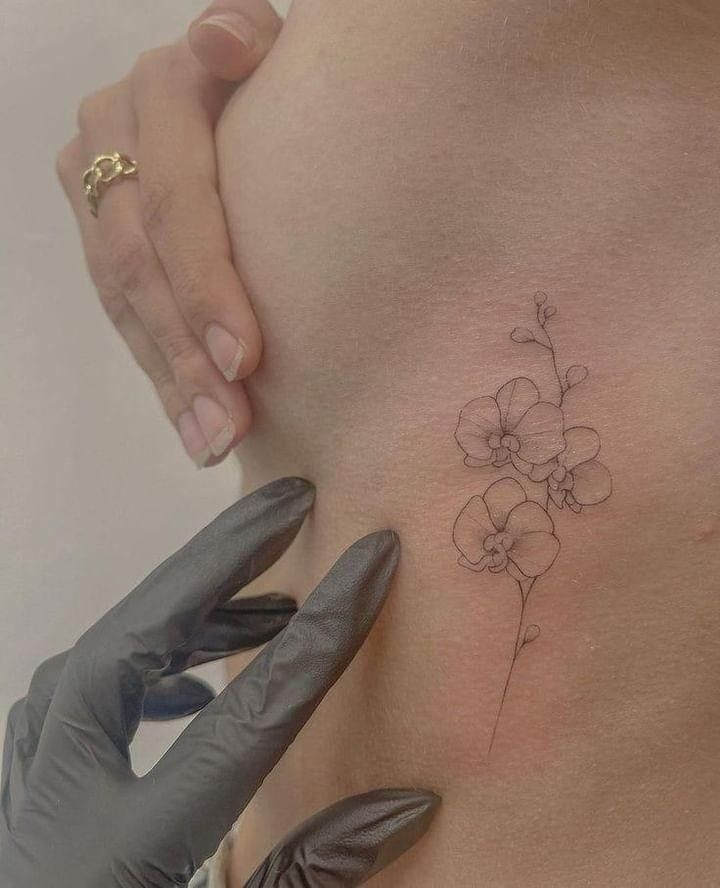 a woman's stomach with a flower tattoo on the side and her hands in gloves