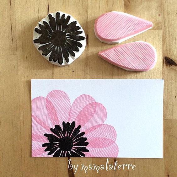 some pink and black flowers are on a wooden table next to two rubber stamps, one with a flower