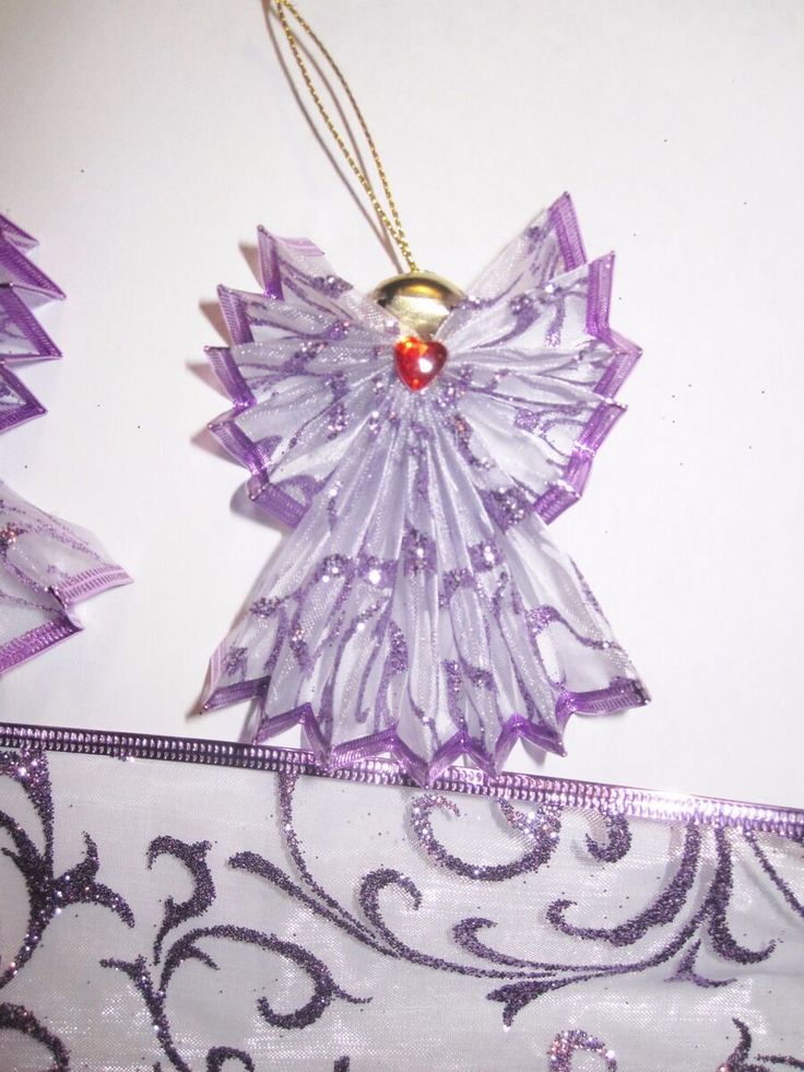 a purple angel ornament hanging on a white wall next to some decorative items