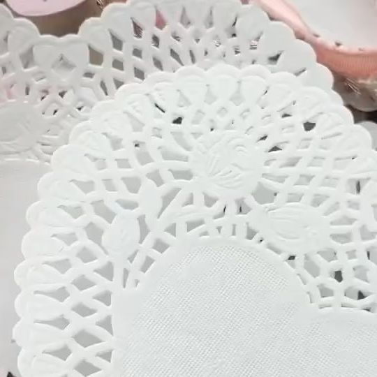 some white doily sitting on top of a table next to pink and white plates