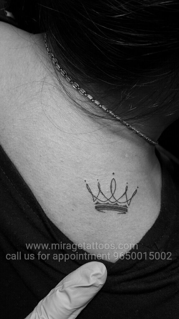 a woman's neck with a crown tattoo on her left side ribcage