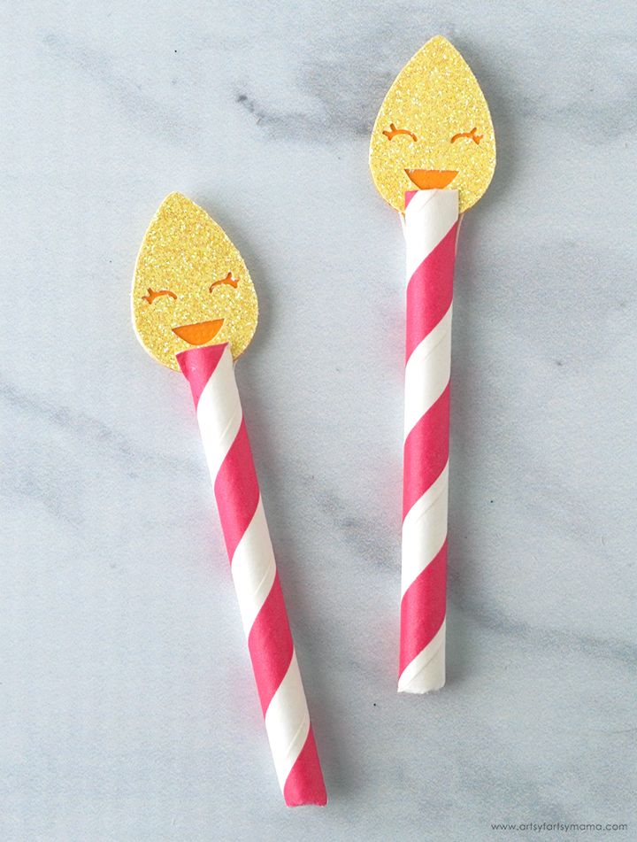 two pink and white striped straws with yellow faces on them, one has a candy cane in the shape of a smiley face