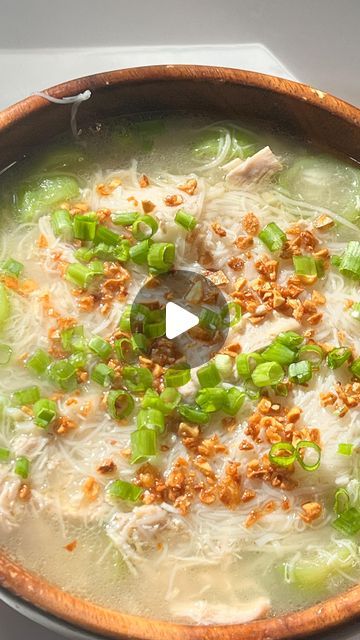 a bowl filled with soup and vegetables on top of a stove next to a spoon