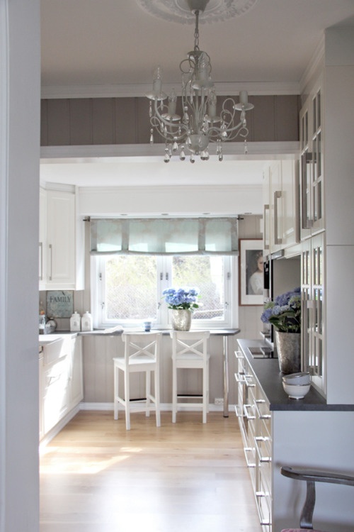 a kitchen with white cabinets and a chandelier hanging from the ceiling above it