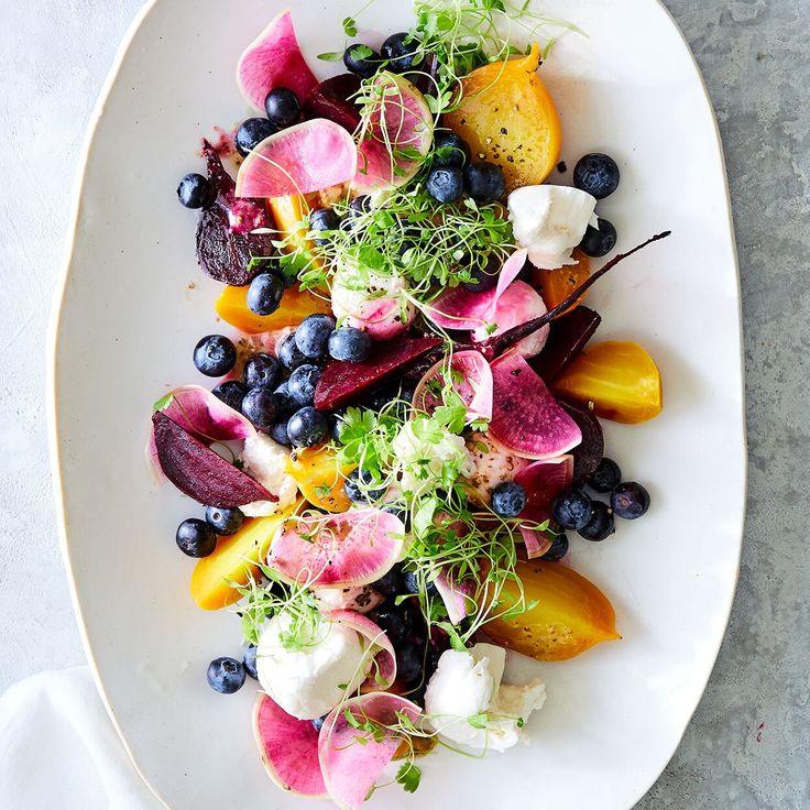 a white plate topped with blueberries, peaches and other vegetables on top of a table