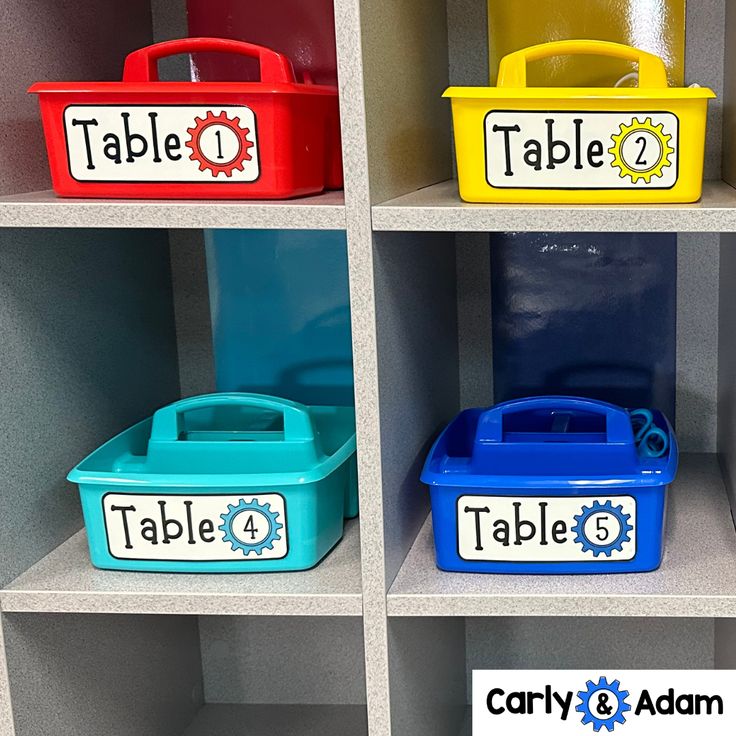 four bins with name labels on them are in a shelf next to each other