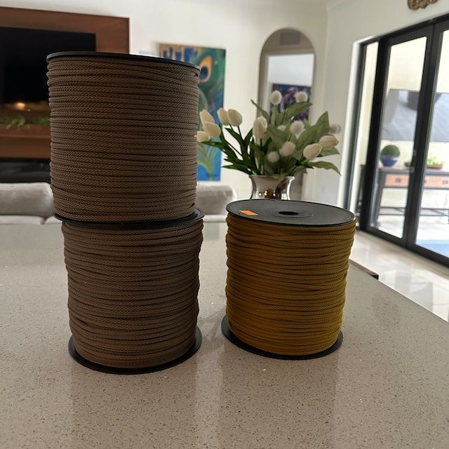 two spools of rope sitting on top of a counter next to a vase with flowers