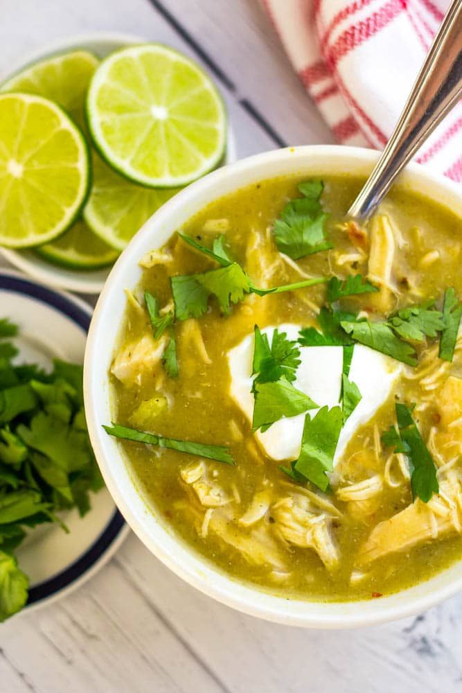 a bowl of chicken tortilla soup with sour cream and cilantro on the side