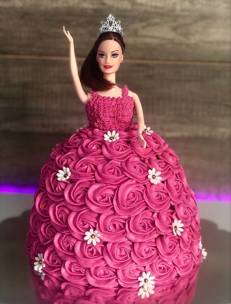 a barbie doll cake with pink frosting and white flowers