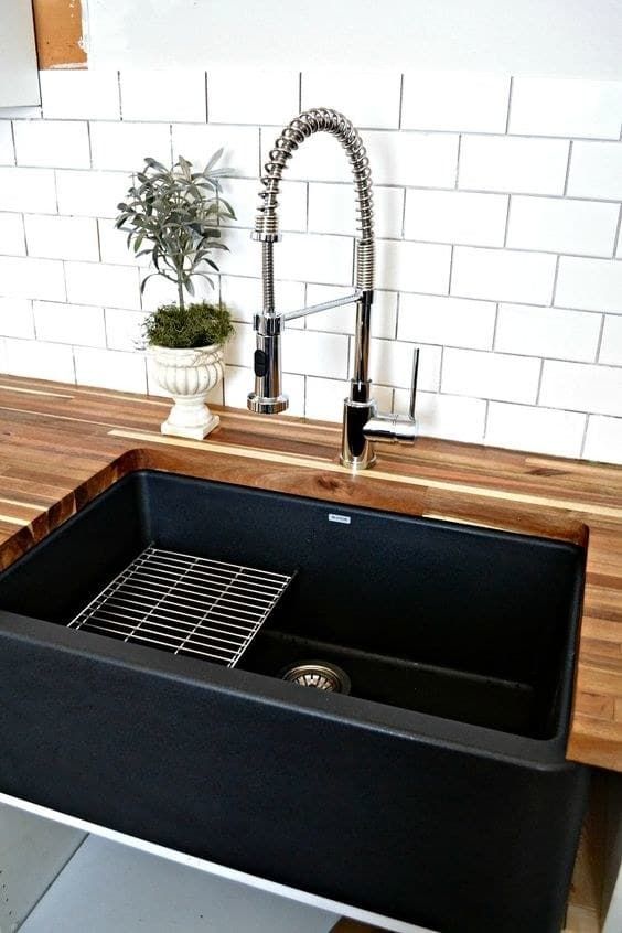 a black kitchen sink sitting under a faucet next to a wooden counter top