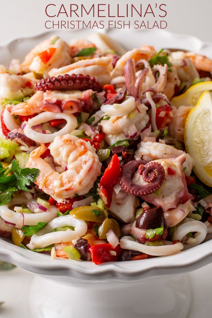 a white bowl filled with shrimp and vegetables on top of a table next to lemon wedges