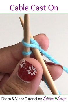 a hand holding a pair of knitting needles with red and white nail polish on it