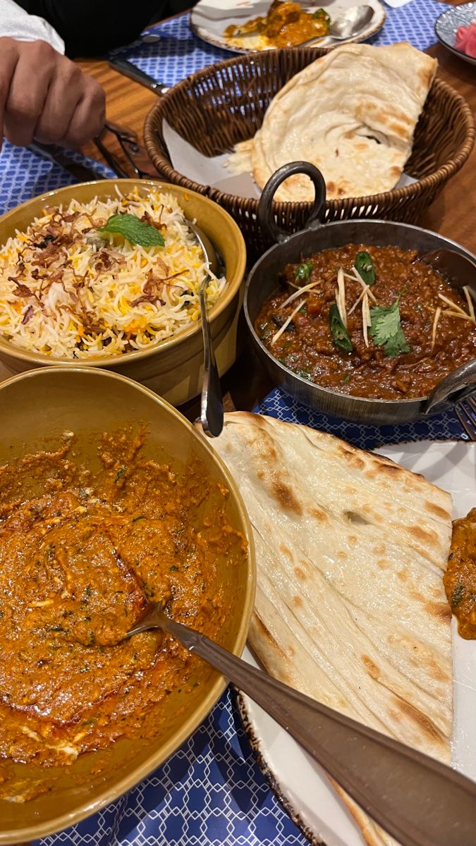 a table topped with lots of different types of food next to breads and bowls