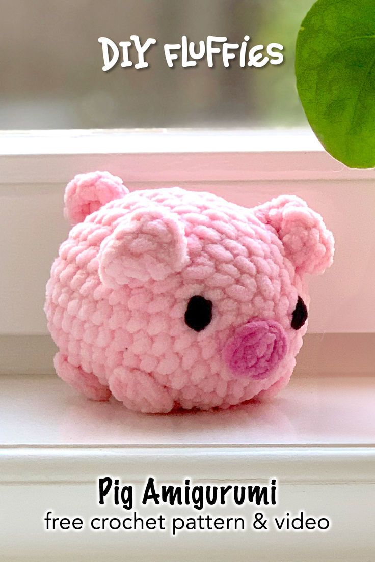 a pink crocheted pig sitting on top of a window sill next to a green leaf