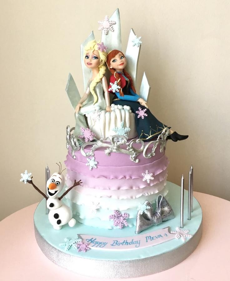 there is a cake that has two girls on it and snowflakes around the edges