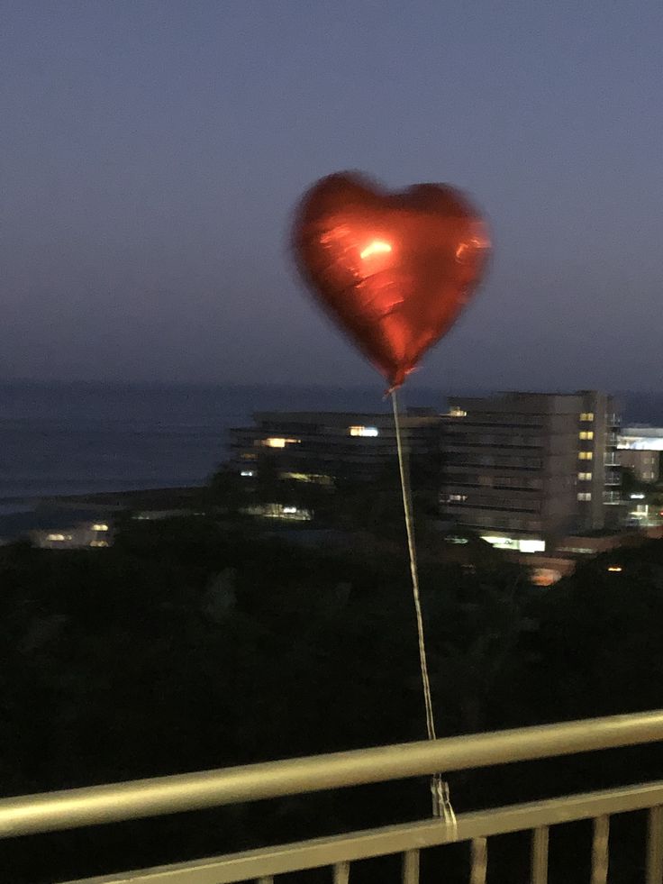 a red heart shaped balloon floating in the air