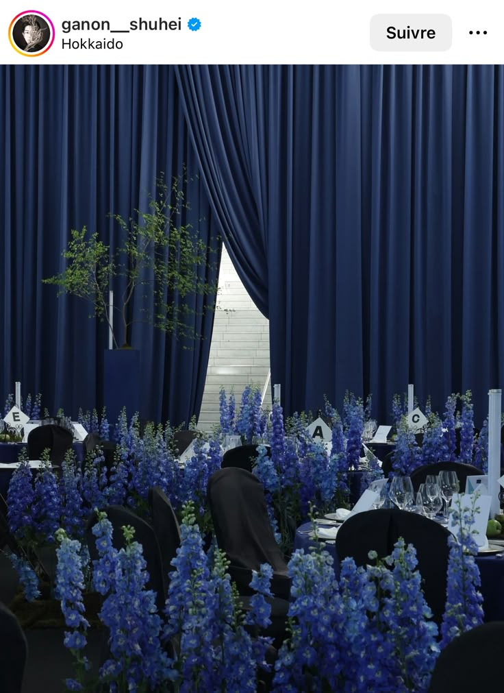 a room filled with tables and chairs covered in blue drapes next to tall windows