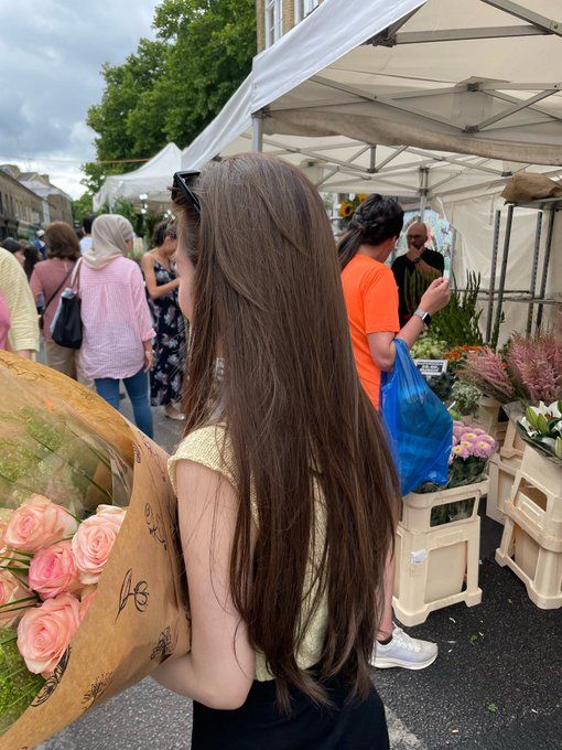 a woman is carrying flowers at an outdoor market