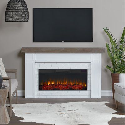 a living room with a fireplace and television mounted on the wall, along with a cow hide rug