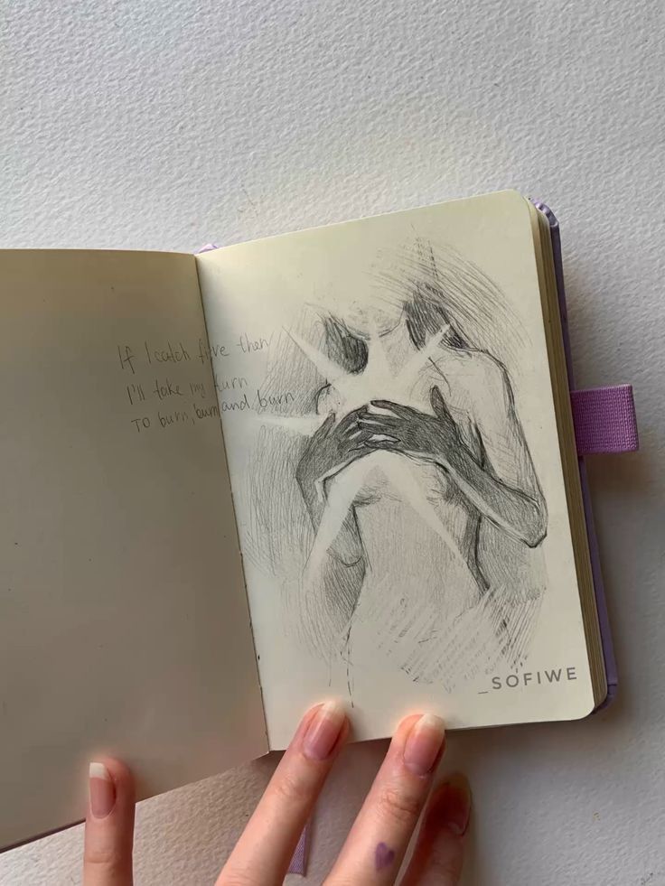 a person holding an open book with a drawing on it