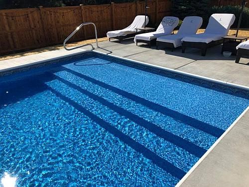 an empty swimming pool with lounge chairs around it