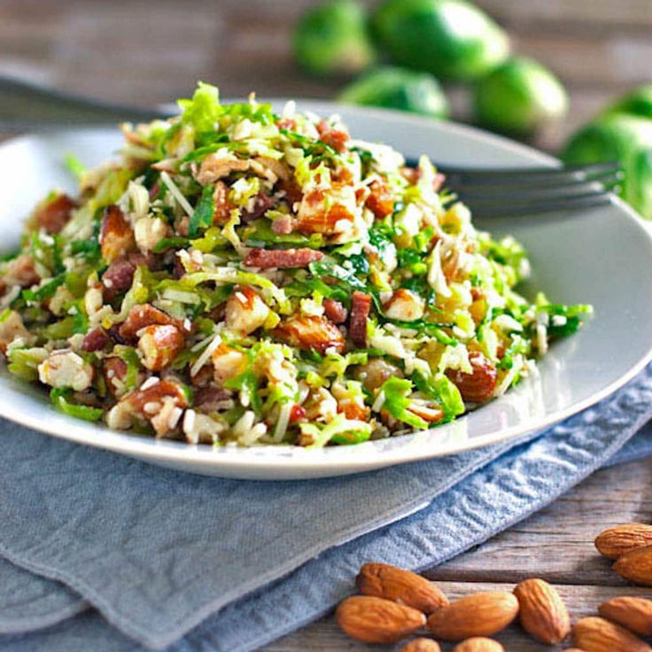 a white plate topped with salad next to almonds