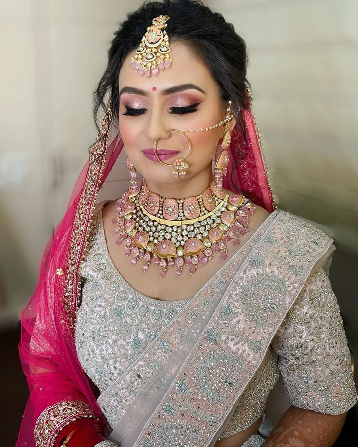 a woman in a white and pink bridal outfit with jewelry on her head,