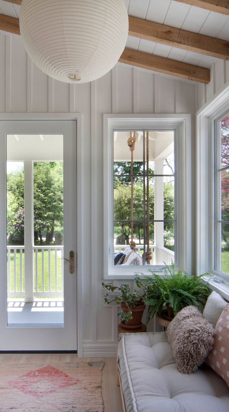 a living room filled with furniture and windows next to a white door covered in wood planks