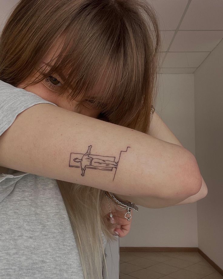 a woman with a tattoo on her arm is looking down at the ground and has an airplane drawn on it