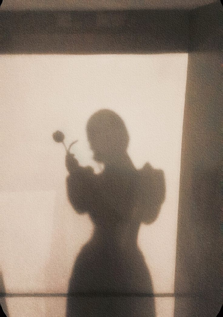 the shadow of a person holding a flower