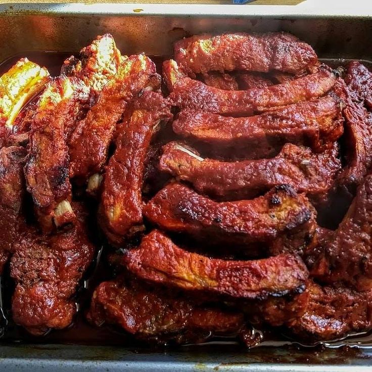 some meat is in a metal pan on the stove top and ready to be cooked