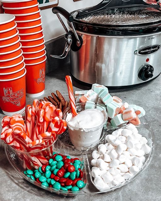 candy and marshmallows are on a plate next to a crock pot