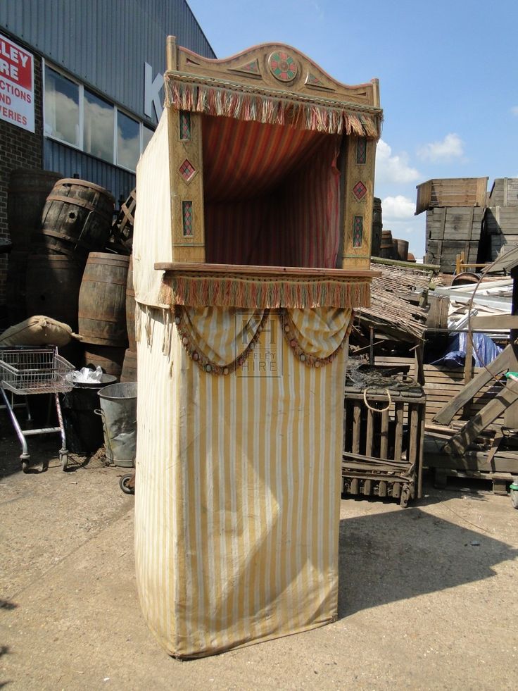 an old fashioned wooden box with curtains on it's sides in front of a pile of junk