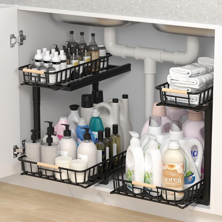 two black baskets filled with cleaning products under a sink