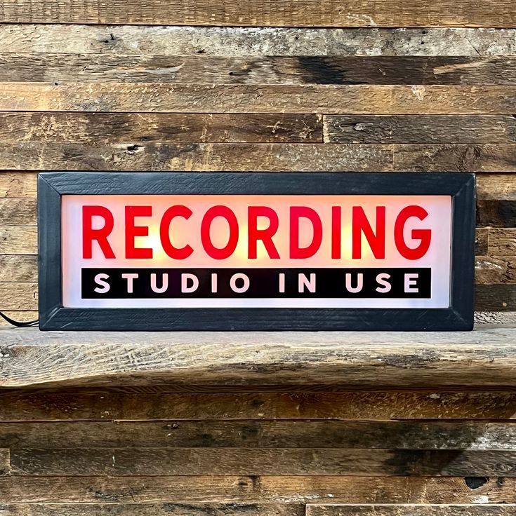 a sign that reads recording studio in use on the side of a wooden wall with planks