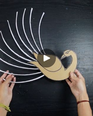 someone is making a bird out of cardboard on a black surface with white strips and scissors